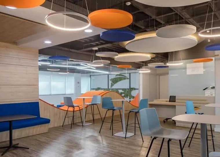 Nuvens acústicas redondas em laranja, azul e bege suspensas sobre um espaço de coworking