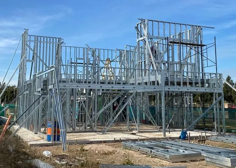 Casa em construção com a estrutura de steel frame montada, sob céu azul