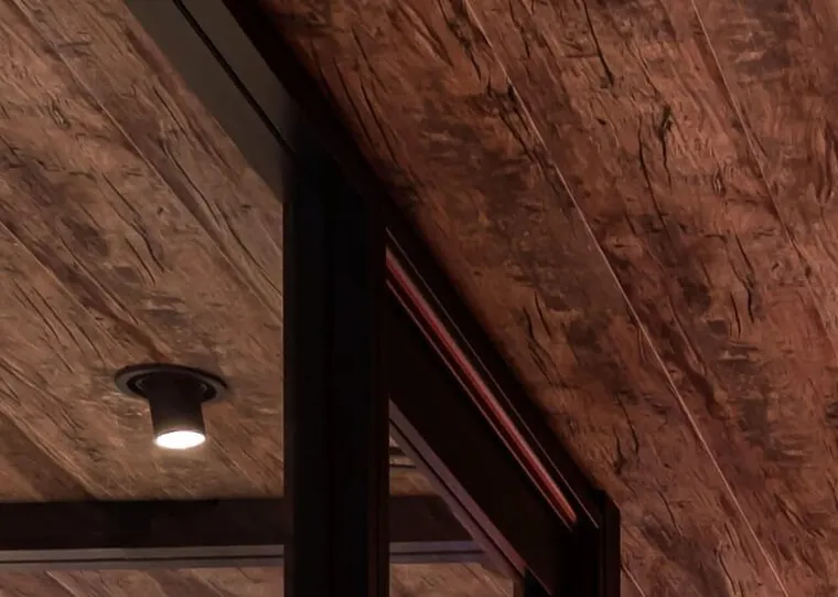 Teto vinílico com textura de madeira escura e spot embutido